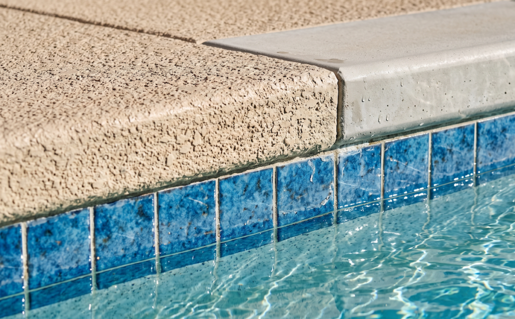 Close-up of textured cool deck coating beside pool coping in an Arizona backyard